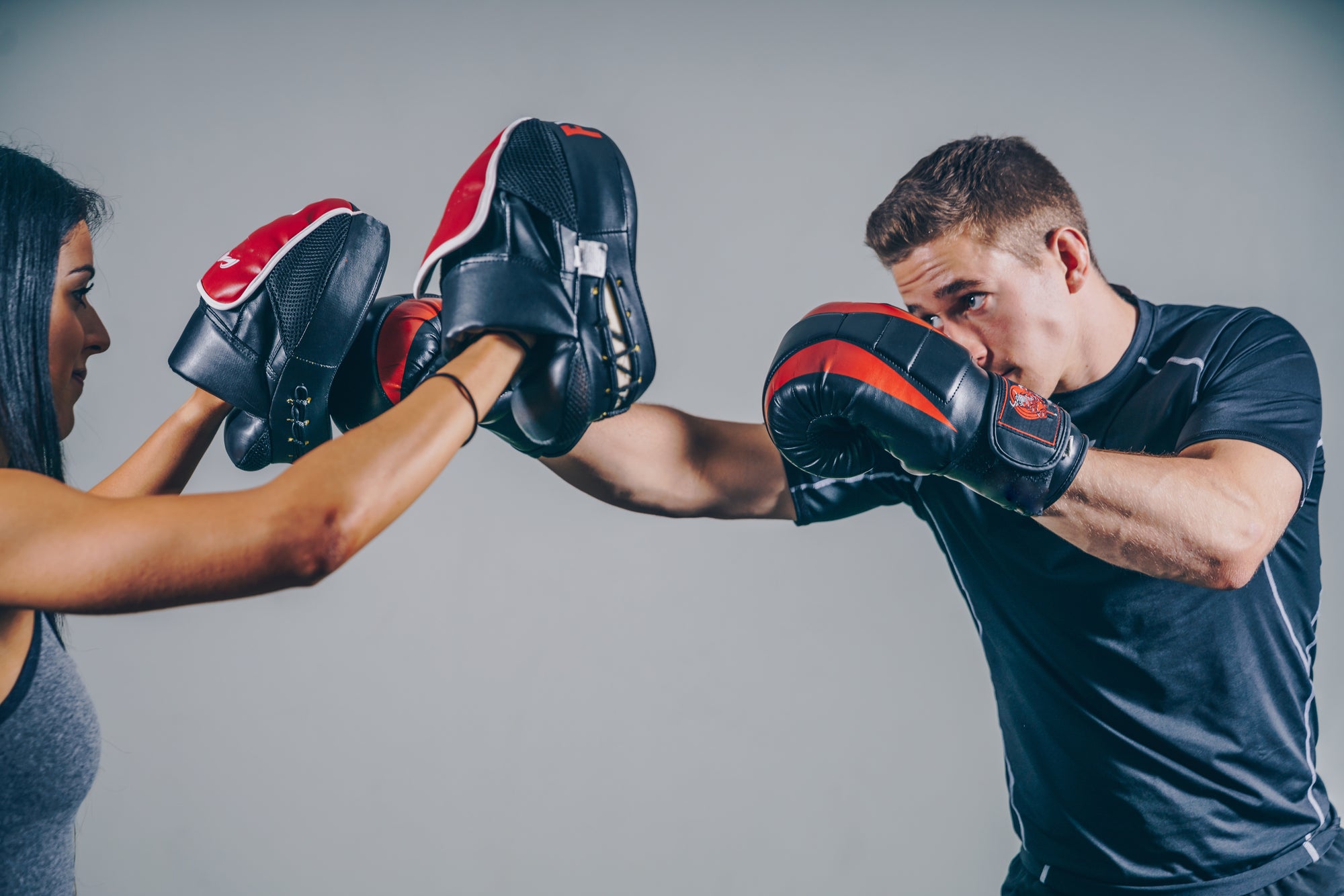 Two people sparring with boxing gloves and focus mitts during a gym workout