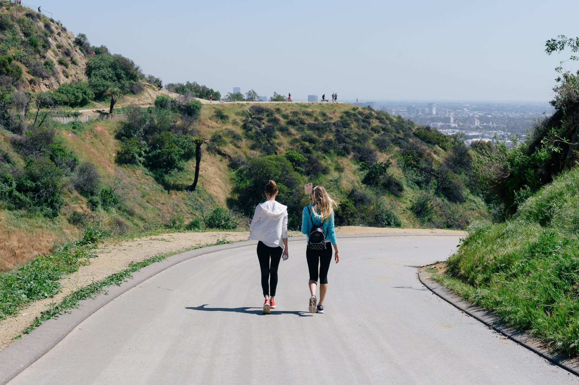 Two friends walking together on a scenic road outdoors